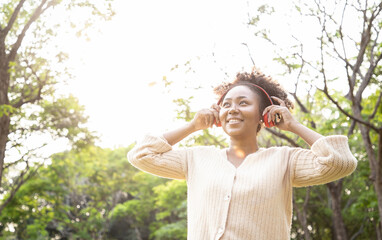 Charming African woman listening favorite songs while traveling to natural attractions with sunny in the public park. Journey of travel and environment studies.