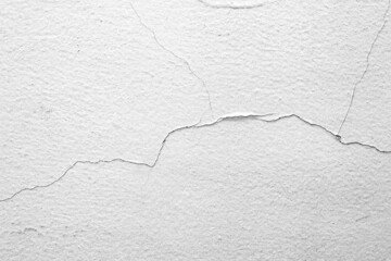 The white concrete wall is cracked, the paper is cracked