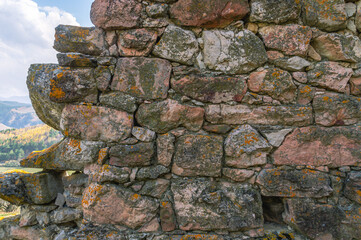 The wall of an ancient tower built of stones in the mountains to protect against attack. Ancient masonry. An ancient structure high in the mountains.