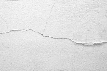 The white concrete wall is cracked, the paper is cracked