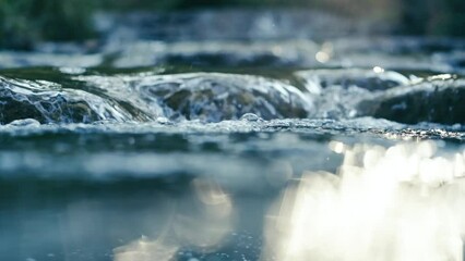 Clear stream running through stone boulders Abundant river flowing on stone bottom in slow motion. Wild mountain river water splashing in summer day.underwater bubbles. split view.. 4K. - Powered by Adobe