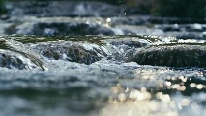 Clear stream running through stone boulders Abundant river flowing on stone bottom in slow motion. Wild mountain river water splashing in summer day.underwater bubbles. split view.. 4K. 1