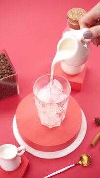 Vertical video: pouring milk into a glass with ice 