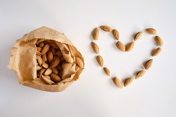 Almonds in a craft paper bag and a heart of nuts on a light background. Healthy food. Healthy vegetarian natural snack. organic food. Nuts close-up