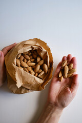 Nuts almonds in a craft paper bag on a light background. Healthy food. Healthy vegetarian natural...