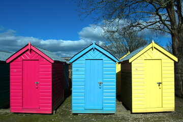 Fototapeta na wymiar Traditional, old fashioned seaside beach huts. Typical British beach scene at Abersoch, north Wales on a sunny spring day. Close up view