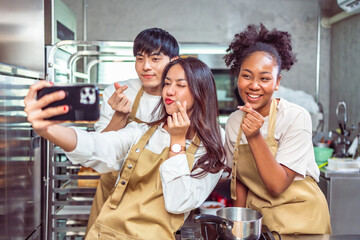 Students In Cookery Class Mixing Ingredients For Recipe In Kitchen.Group of young people taking selfie during cooking classes.