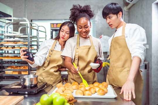 Students In Cookery Class Mixing Ingredients For Recipe In Kitchen.Group of young people taking selfie during cooking classes.