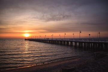 Naklejka na ściany i meble Colorful seaside morning landscape. Wooden pier on the sea at sunrise.