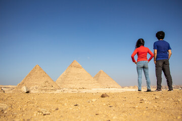 Couple looking at the panoramic view of the pyramids, Giza, Cairo, Egypt - obrazy, fototapety, plakaty