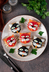 Tartlets Kittens with cheese, egg and caviar on a round plate on brown background, Top view