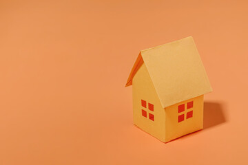 Orange paper house with copy space. The concept of buying a sale and a loan for a house. Minimal concept and pastel color.