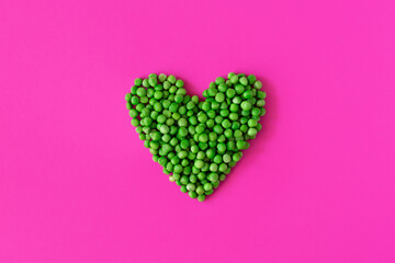 Top view of fresh green peas. Heart shaped green peas isolated on pink background. Space to write text font
