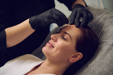 Obraz na płótnie Canvas Close-uo of a happy middle aged beautiful woman taking care of her face skin in modern wellness spa salon. Anti-aging anti wrinkles and rejuvenationg beauty treatment. Health care and medicine