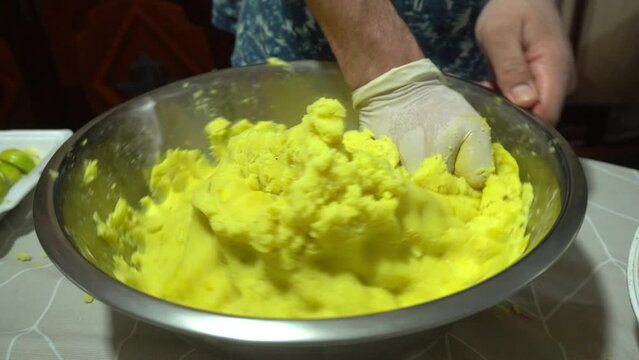 closeup kneading yellow potatoes by hand to prepare Causas from Lima, typical Peruvian food in 4k
