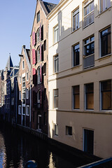 Fototapeta na wymiar Row tall old brick canal houses with red wooden shutters and a water canal in Amsterdam. Famous scenic view.
