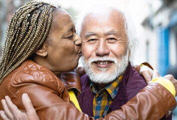 Happy multiracial senior couple having tender moments in city - Elderly people and love relationship concept