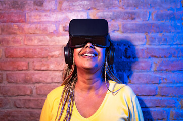 Senior African woman playing with virtual reality glasses - Tech gaming entertainment concept