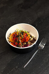 Three meatballs in tomato sauce with wild rice close-up on a black background in eco paper black bowl with fork. Healthy food delivery service and daily ration concept.