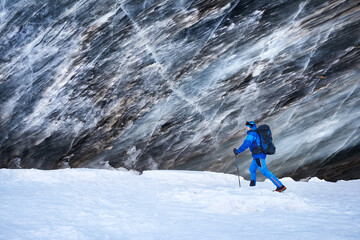 Tourist near ice wall at winter mountains