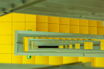 View from height between yellow stairs. The hole between the stairs with yellow tiles on several...