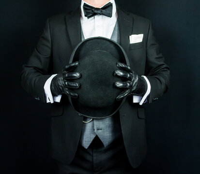 Portrait of Butler in Dark Suit and Leather Gloves Holding Bowler Hat. Classic and Eccentric English Gentleman.