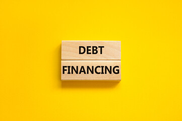 Debt financing symbol. Concept words Debt financing on wooden blocks on a beautiful yellow table yellow background. Business finance and debt financing concept, copy space.