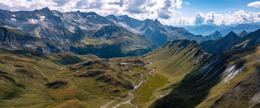 Aerial panoramic view towards the Capanna Motterascio, an alpine hut on the Greina plateau in Blenio, Swiss Alps. A rocky ridge on the right leads the eye towards the river that flows in the valley.