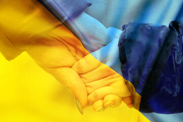 Mother holds a little girl by the hand against the background of the national flag of Ukraine...