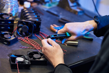 A master technologist makes fans for a computer cooling system. Computer Fan Parts lie on the table