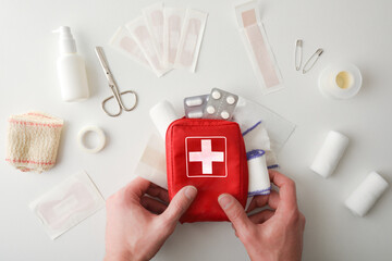 Hands picking up travel first aid bag on white table