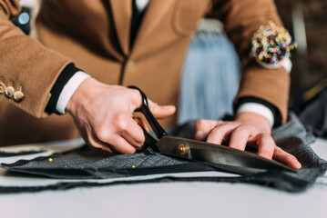 Maßschneider schneidet Anzug Stoff mit Schere in Form horizontal