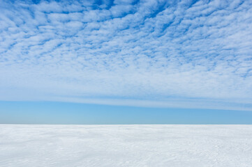 background spring landscape. white snowy field and blue sky with clouds