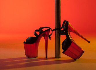 Shoes for a strip, pole dance in heels near the pylon on a red-yellow background