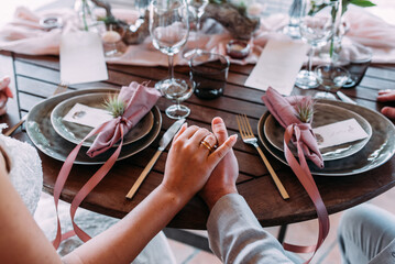 Frisch verheiratetes Paar sitzt am Tisch Hand in Hand beim Abendessen in Rosa