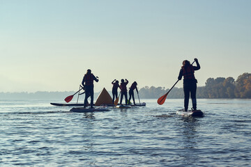 Silhouette of group of children paddle with SUP stand up paddle board in the river. SUP...