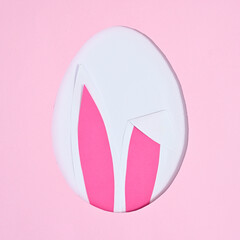 Easter creative concept. Egg shape with bunny ears on pastel pink background. Flat lay