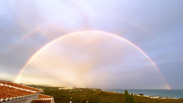 Beautiful rainbow after rain in the region of Malaga Andalusia Benajarafe. Coast line beach at mediterranean sea. View from the roof house. 