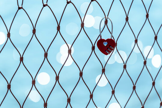 Red heart shaped padlock on a fence conceptual love forever.