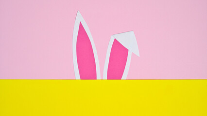 Bunny ears on pastel pink and yellow background. FLat lay minimal creative concept