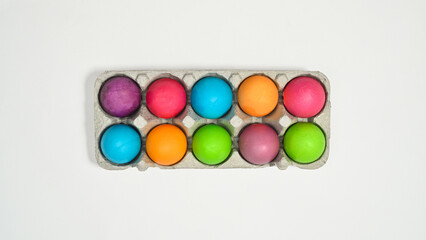 Fototapeta na wymiar Colorful Easter eggs in card box on white background. Flat lay