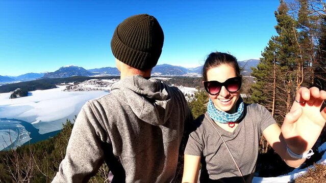 A couple ejoying the sun and the scenic view on the frozen Faak lake and the Karawanks in Carinthia in Austrian Alps, Europe. The picturesque lake is surrounded by high mountains. Freedom. Selfie
