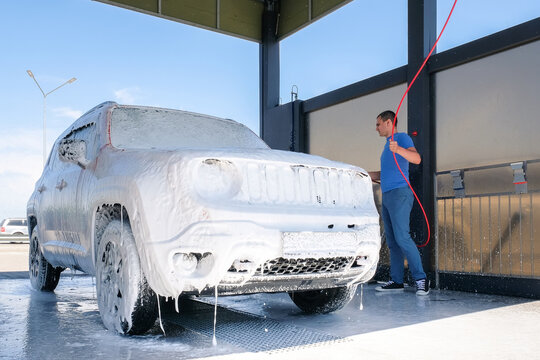 Car in the foam at the car wash. A man washes a car with soap