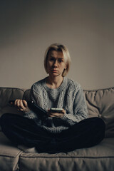 Obraz premium Stop the war. Pray for Ukraine. we are available to Ukraine. Ukrainian frightened woman reads war news on her phone. The woman is afraid of the sounds of air raids and explosions. The concept of fear 