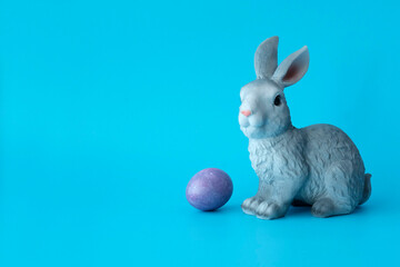 Easter rabbit, toy next to the colored eggs. Illustration for the Easter holidays. Copyspace.