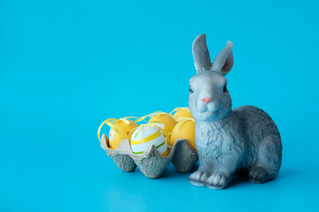 Easter rabbit, toy next to the colored eggs. Illustration for the Easter holidays. Copyspace.
