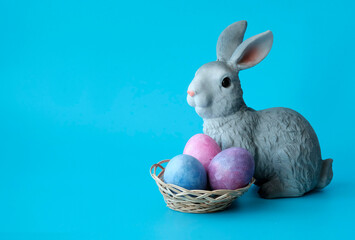 Easter rabbit, toy next to the colored eggs. Illustration for the Easter holidays. Copyspace.