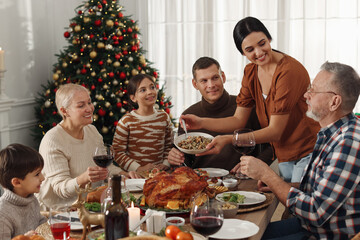 Woman with bowl of traditional Christmas kutia and her family during festive dinner at home. Slavic dish