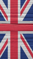 Fragment of British flag on a dry wooden surface. Natural vertical background. Mobile phone wallpaper made of old wood. The official symbol of the Great Britain. Solar lighting with hard shadows