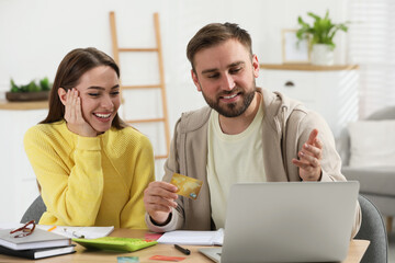 Young couple discussing family budget at table in living room